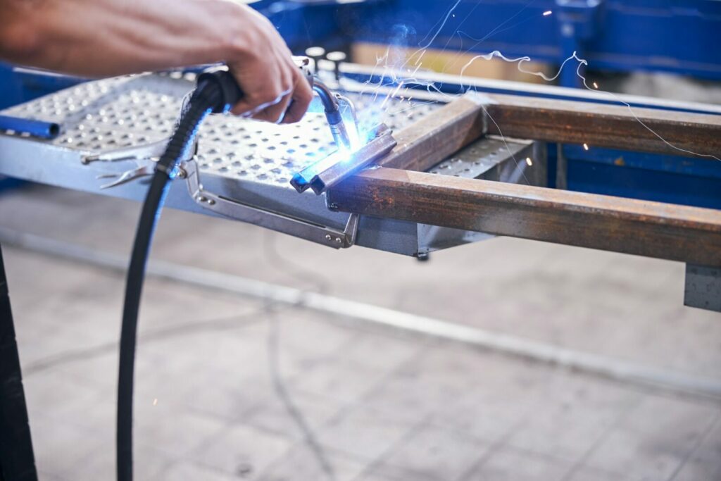 Male worker welding metal tools in garage